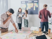 A group of people using a kanban board and a whiteboard to manage a project.