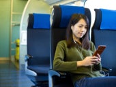 Woman sitting in transit bus seat looking at cellular phone.