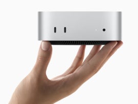 The new Mac mini held up by hand.